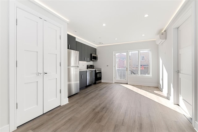 kitchen with baseboards, light countertops, appliances with stainless steel finishes, dark cabinets, and light wood finished floors
