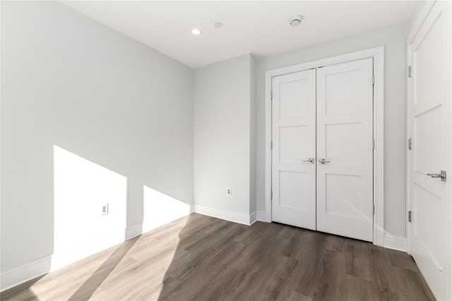unfurnished bedroom featuring a closet, baseboards, recessed lighting, and wood finished floors