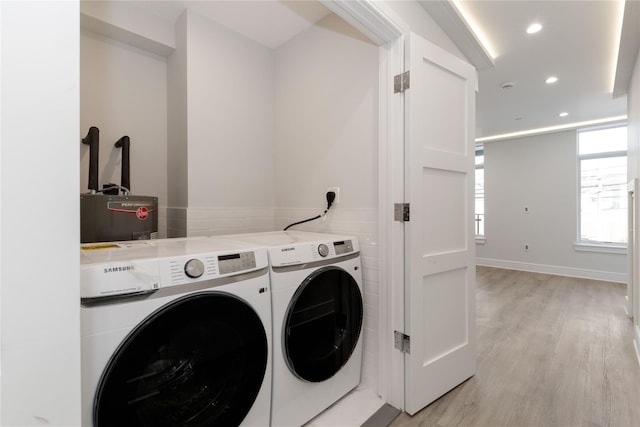 laundry area featuring a wealth of natural light, light wood-style flooring, washer and clothes dryer, and laundry area