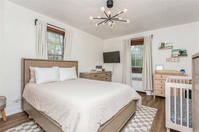 bedroom with wood finished floors, a chandelier, radiator, and baseboards