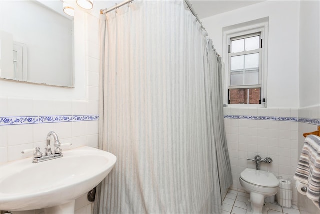 bathroom with tile walls, a sink, tile patterned flooring, toilet, and curtained shower