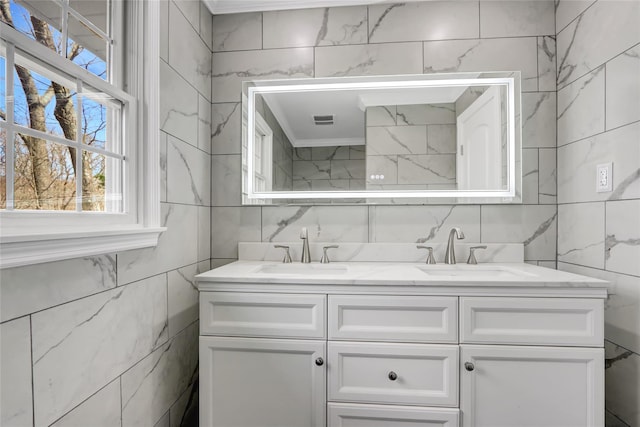 full bathroom with a sink, visible vents, tile walls, and crown molding