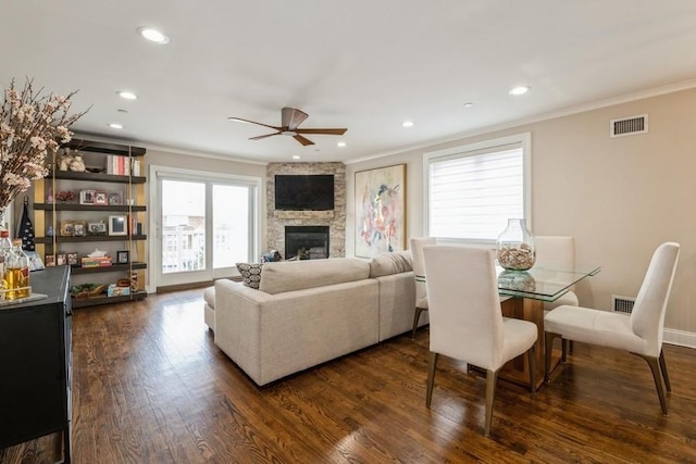 living room with ornamental molding, a fireplace, dark wood-style floors, a ceiling fan, and visible vents
