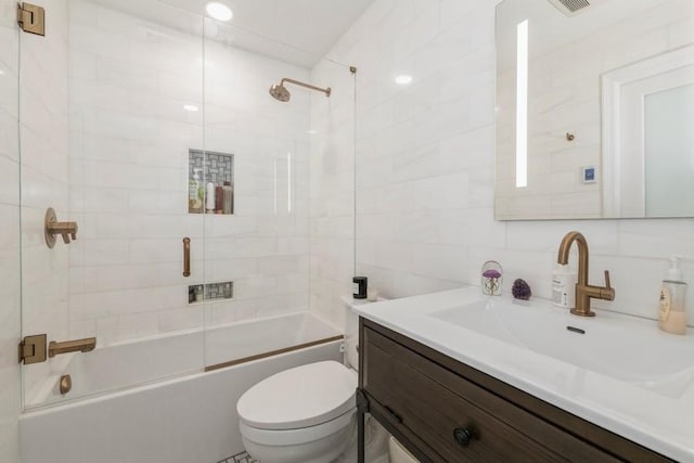 bathroom with bath / shower combo with glass door, tasteful backsplash, vanity, toilet, and tile walls