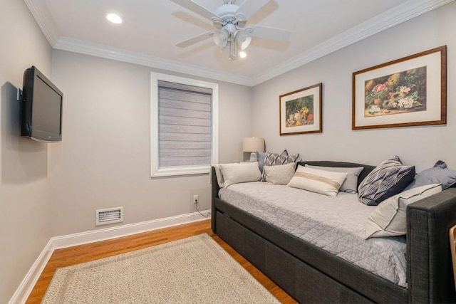 bedroom featuring ornamental molding, visible vents, baseboards, and wood finished floors