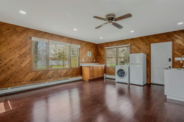 laundry area featuring washer / clothes dryer, a baseboard radiator, wood walls, and a baseboard heating unit