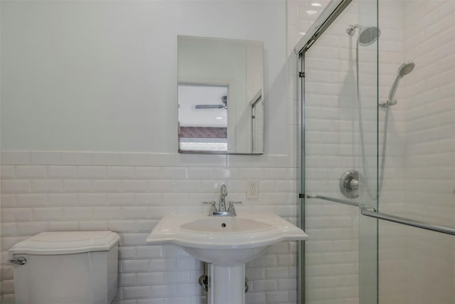 bathroom with a sink, tile walls, toilet, and a shower stall