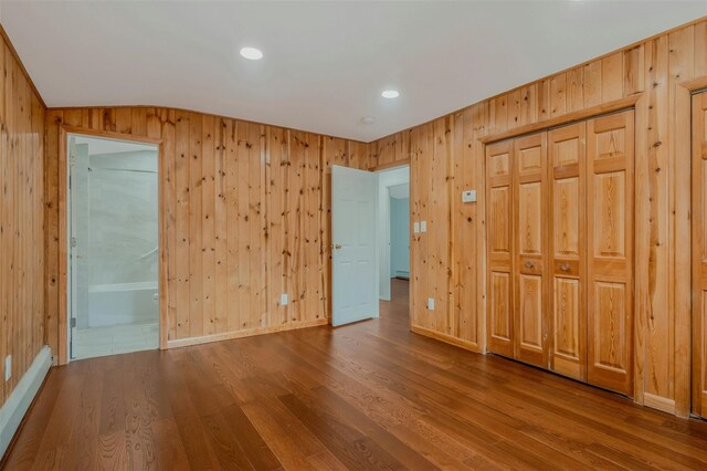 unfurnished bedroom featuring ensuite bathroom, recessed lighting, vaulted ceiling, wood finished floors, and wood walls