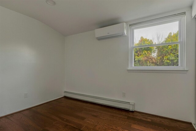 spare room featuring a wall mounted air conditioner, a baseboard heating unit, vaulted ceiling, and wood finished floors