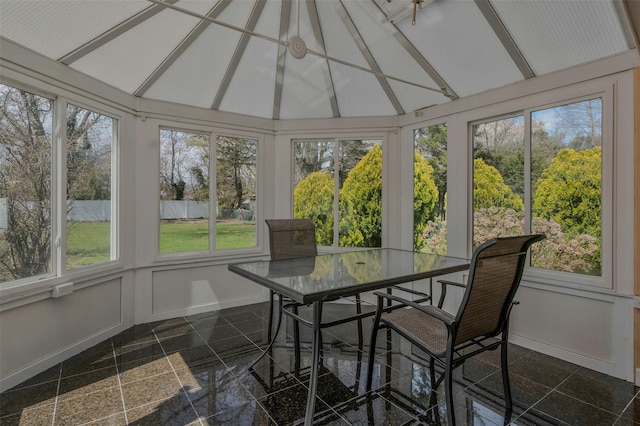 sunroom / solarium with a healthy amount of sunlight, granite finish floor, and lofted ceiling with beams