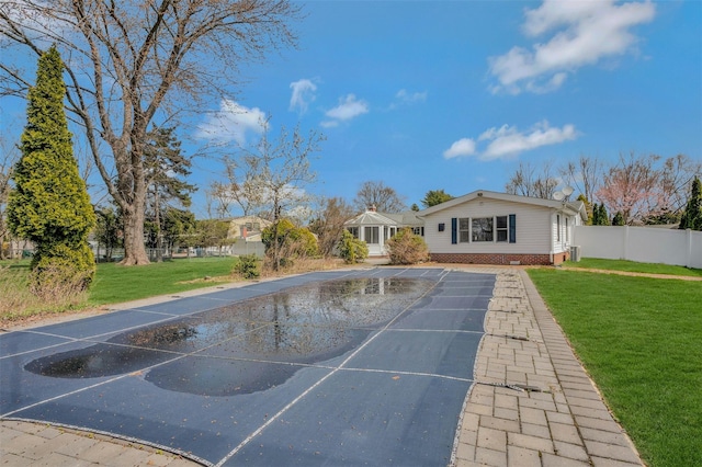 rear view of house with uncovered parking, a yard, and fence