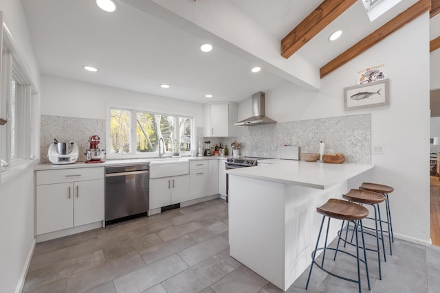 35 Turtle Cove Ln, Huntington, NY 11743 - kitchen featuring dishwasher, wall chimney exhaust hood, a peninsula, tasteful backsplash, and white cabinetry