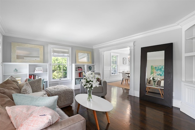 living area with built in features, crown molding, wood finished floors, and ornate columns
