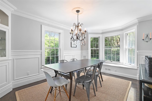 dining space with a chandelier, crown molding, a wainscoted wall, dark wood-style floors, and a decorative wall