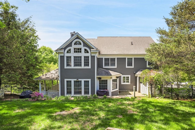 rear view of house with a chimney, a shingled roof, and a patio