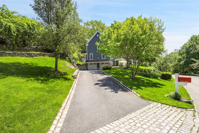 view of property hidden behind natural elements with asphalt driveway, a front yard, and a garage
