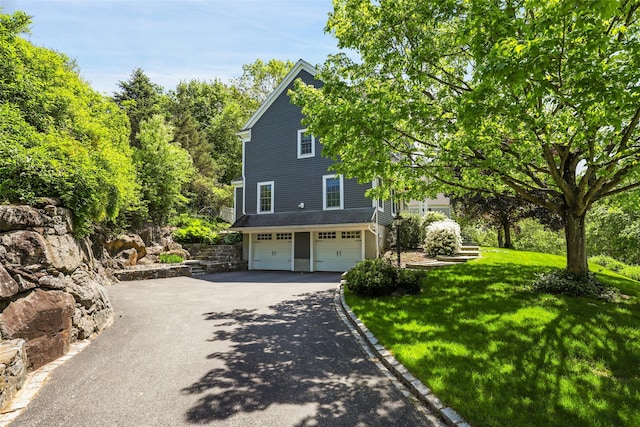 view of front facade with driveway, a garage, and a front yard
