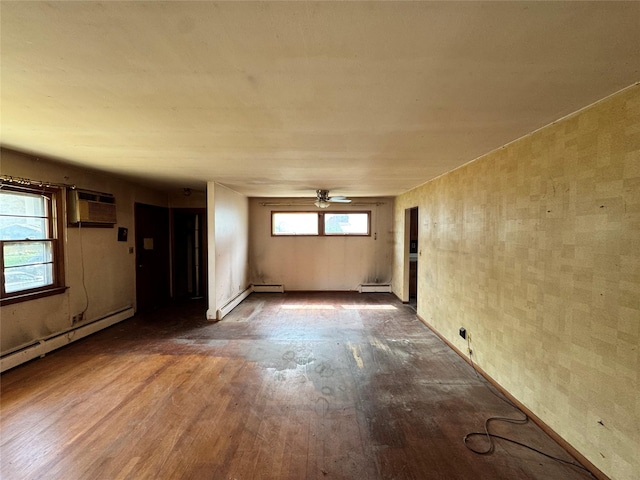 empty room with a baseboard radiator, wood finished floors, a ceiling fan, and a wall unit AC