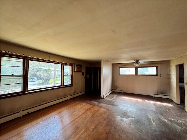 interior space with baseboard heating, wood finished floors, a wall mounted AC, and ceiling fan