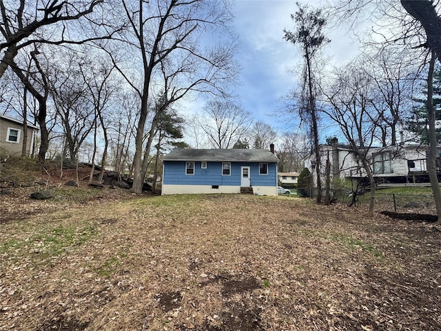 rear view of house featuring crawl space and a shingled roof