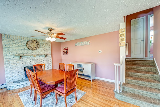 dining space featuring light wood-style flooring, a textured ceiling, stairway, baseboards, and ceiling fan