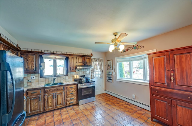 kitchen with a sink, a baseboard heating unit, freestanding refrigerator, plenty of natural light, and electric stove