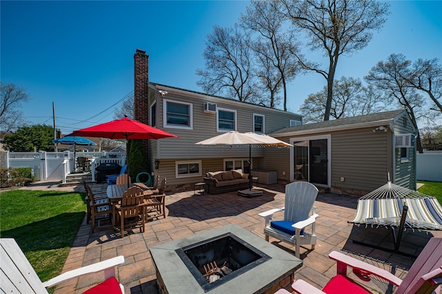 back of property featuring a gate, fence, a chimney, an outdoor living space with a fire pit, and a patio area
