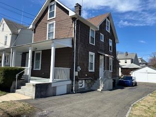 30 Treno St, New Rochelle, NY 10801 - view of front facade featuring a garage, a porch, an outdoor structure, and a chimney