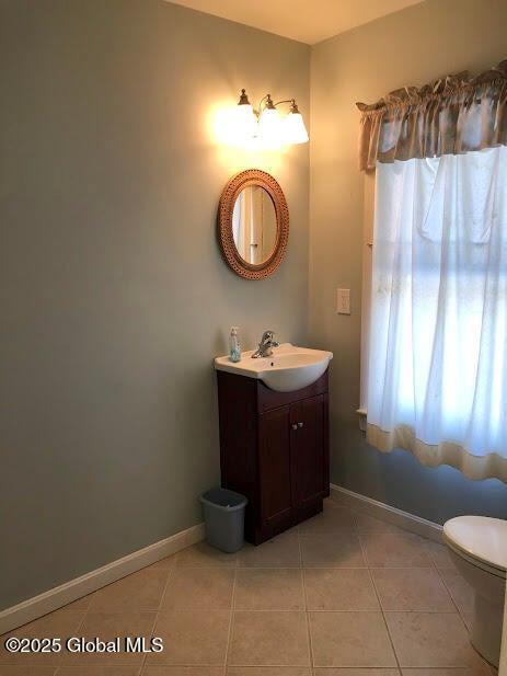 bathroom featuring vanity, tile patterned flooring, baseboards, and toilet