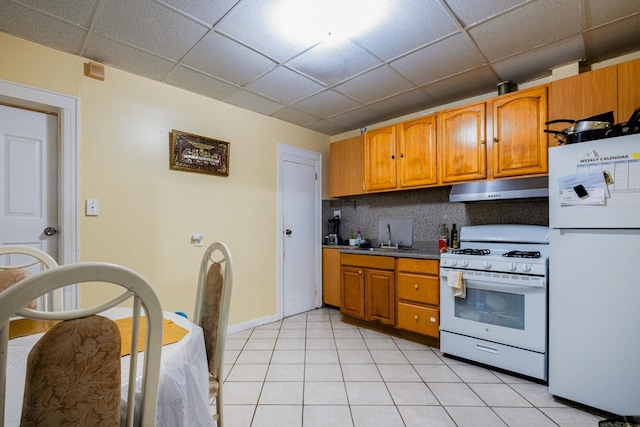 101-14 95th St, Ozone Park, NY 11416 - kitchen featuring white appliances, under cabinet range hood, a drop ceiling, tasteful backsplash, and brown cabinetry