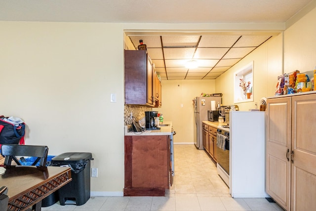 101-14 95th St, Ozone Park, NY 11416 - kitchen with light countertops, gas range oven, a drop ceiling, light tile patterned floors, and freestanding refrigerator