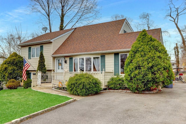 view of front of property with roof with shingles and a front yard
