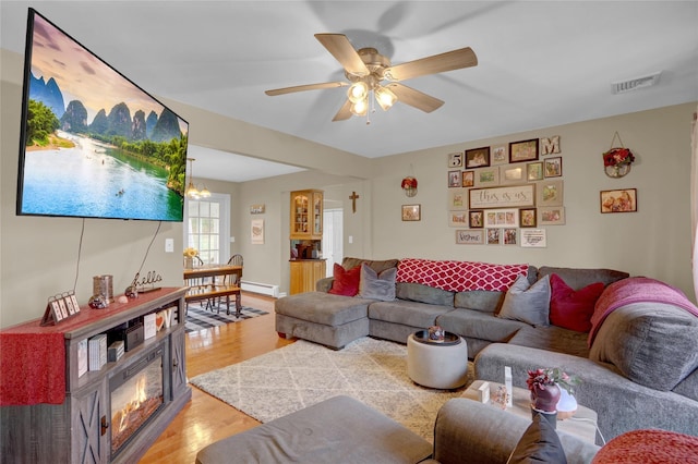 living room featuring visible vents, a baseboard radiator, light wood finished floors, and ceiling fan with notable chandelier