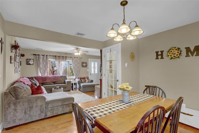 dining room with visible vents, baseboards, light wood-type flooring, and ceiling fan with notable chandelier