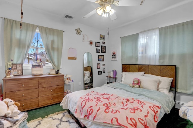 carpeted bedroom with visible vents, ceiling fan, arched walkways, and baseboard heating