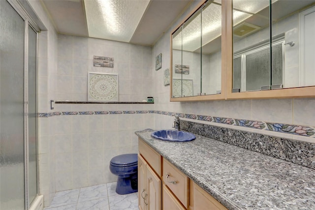 full bath featuring vanity, tile walls, toilet, a shower stall, and marble finish floor