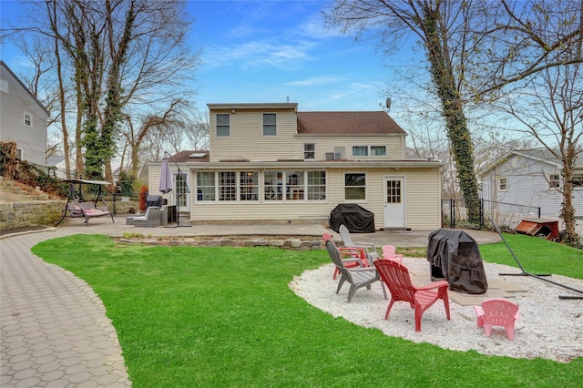 rear view of property featuring a patio area, a yard, fence, and an outdoor fire pit