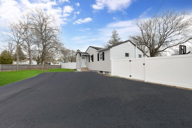 view of side of home with entry steps, aphalt driveway, fence private yard, and a gate
