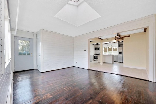 unfurnished living room featuring a skylight, wood finished floors, baseboards, and a ceiling fan