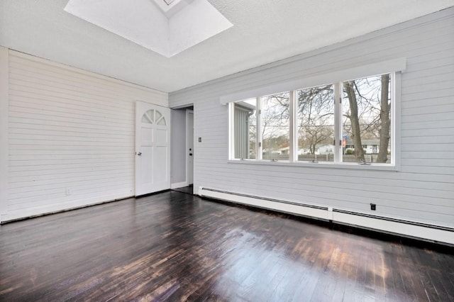empty room with dark wood finished floors, baseboard heating, and a skylight