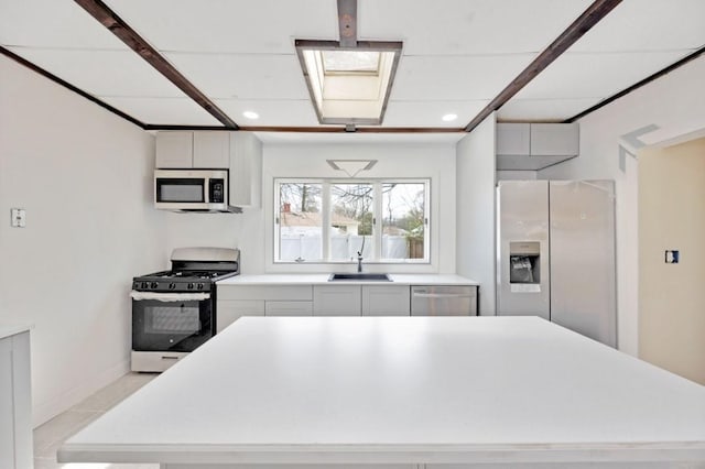 kitchen with white cabinets, a center island, appliances with stainless steel finishes, light countertops, and a sink