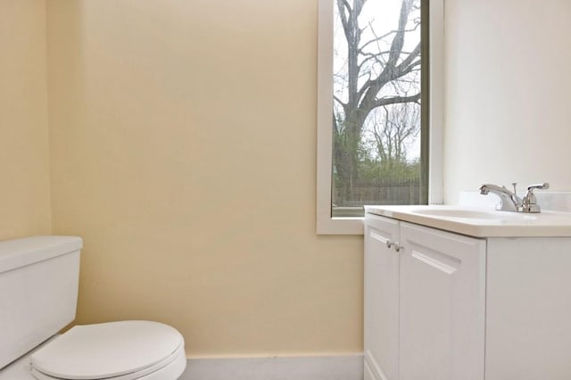 bathroom with toilet, vanity, and baseboards