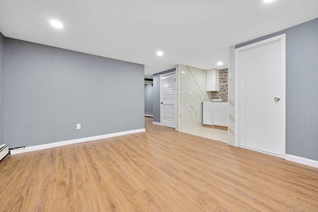 unfurnished living room featuring baseboards, light wood-type flooring, a baseboard heating unit, and recessed lighting