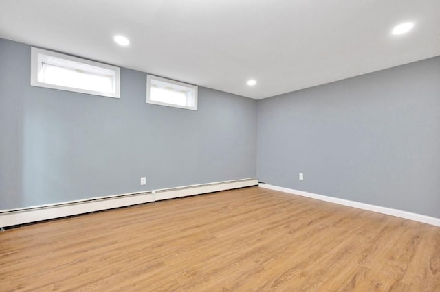 basement featuring a baseboard radiator, wood finished floors, baseboards, and recessed lighting