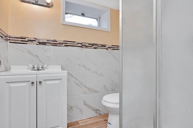 bathroom featuring toilet, tile walls, and vanity