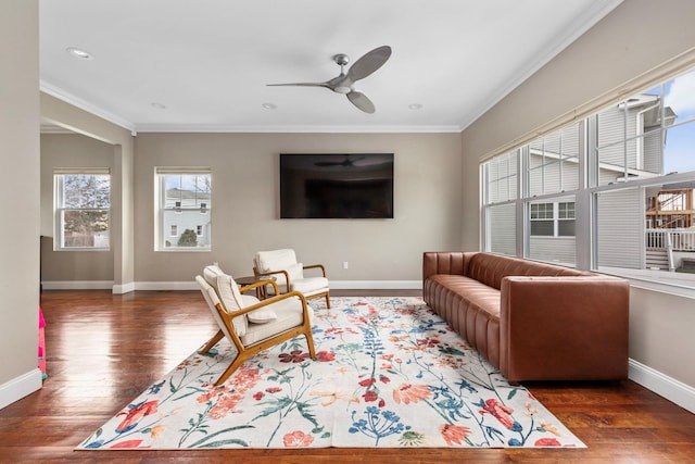 living room featuring baseboards, a ceiling fan, crown molding, and wood finished floors