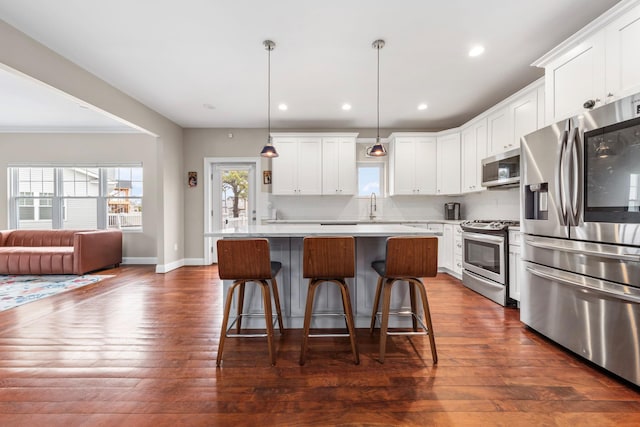 kitchen with a center island, white cabinets, dark wood-style flooring, light countertops, and stainless steel appliances