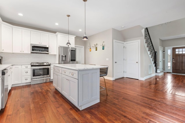 kitchen featuring dark wood-style floors, white cabinetry, a breakfast bar area, and appliances with stainless steel finishes