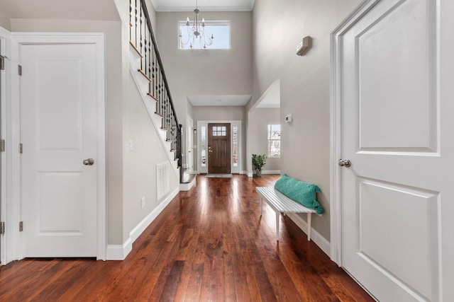 entryway with an inviting chandelier, visible vents, hardwood / wood-style floors, stairs, and baseboards