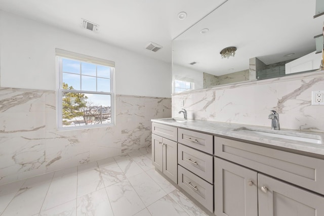 bathroom with a sink, visible vents, tile walls, and a wealth of natural light
